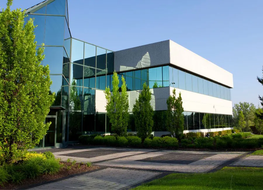 commercial building, lots of trees and bushes and glass windows